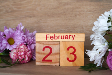 February 23. Wooden calendar with fresh flowers around it. Copy space.