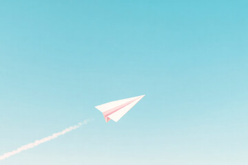 White paper airplane flying upward in clear blue sky, creating a clean minimal scene about dreams, goals, motivation and freedom.