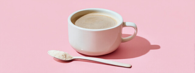 Coffee cup with spoon of powdered colostrum supplement on pastel background for wellness trend. banner 
