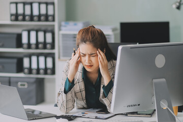 Pain, headache and stressed finance manager feeling sick, tired and worried about a financial problem at her startup company. Young and frustrated professional businesswoman working at an office