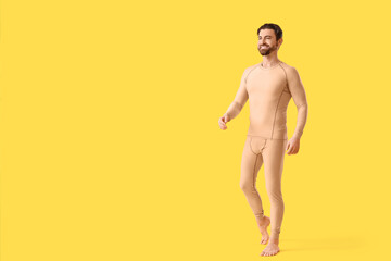 Fototapeta premium Handsome young man in thermal underwear walking on yellow background
