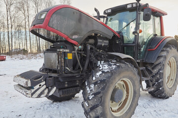 A tractor with an open hood in the snow in winter © ILIA