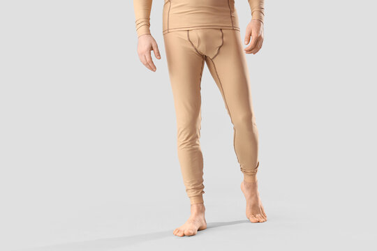 Handsome young man in thermal underwear walking on grey background