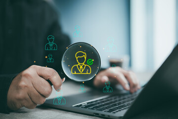 Businessman using magnifying glass to find candidate on laptop for recruitment and hiring process