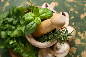 Wooden mortar with different herbs and fresh mushrooms on green background © Pixel-Shot