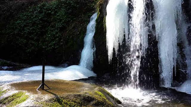 Scenic summer landscape of a beautiful natural waterfall cascade flowing over green forest rocks and mountain stones into a peaceful park stream