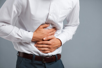 Obraz premium Man holding his stomach in pain, symbolizing abdominal discomfort, illness, and digestive problems