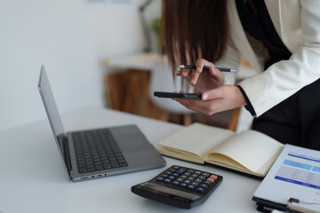 Businesswoman using smartphone managing work data and finances