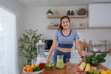 Woman preparing healthy green smoothie in kitchen