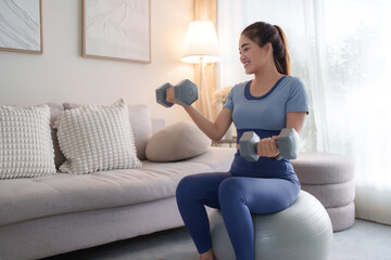 Young woman training strength using dumbbells at home