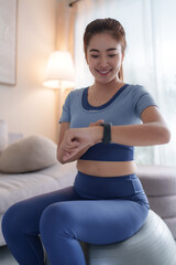 Young woman monitoring fitness progress using smartwatch at home
