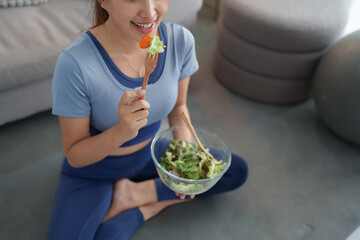 Young woman eating healthy salad after workout