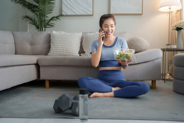 Woman talking on phone after home workout eating salad
