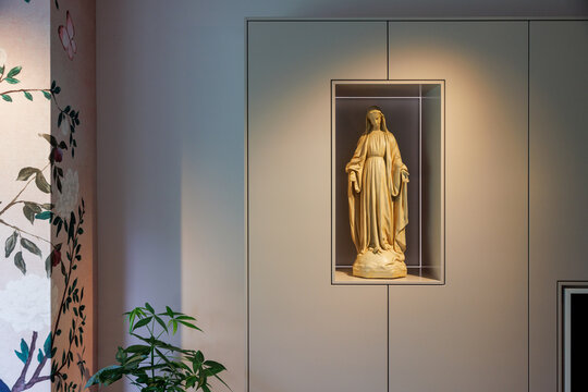 A holy maria figure in a modern cupboard in a house.