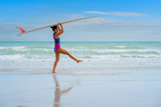 Asian play surf alone on the summer beach. Solo outdoor activity on holiday
