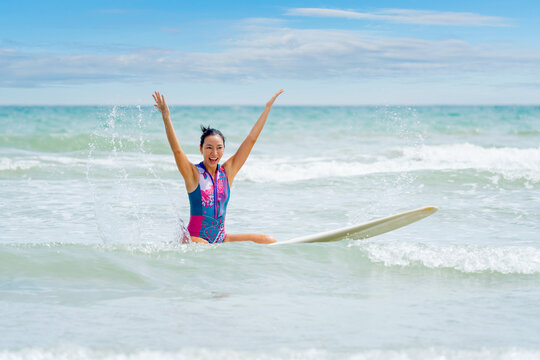 Asian play surf alone on the summer beach. Solo outdoor activity on holiday