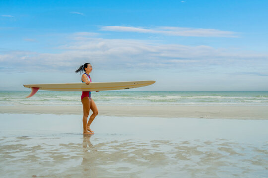 Asian play surf alone on the summer beach. Solo outdoor activity on holiday