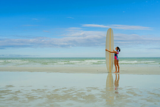 Asian play surf alone on the summer beach. Solo outdoor activity on holiday