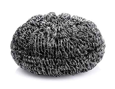 A close-up of a tightly packed, twisted, silver-colored wire pad sits on a stark white surface, casting a soft shadow