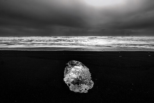A lone chuck of ice on black sand on Diamond Beach, Iceland
