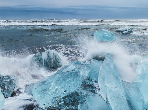 Waves slam amongst large blocks of ice on the shoreline in Iceland