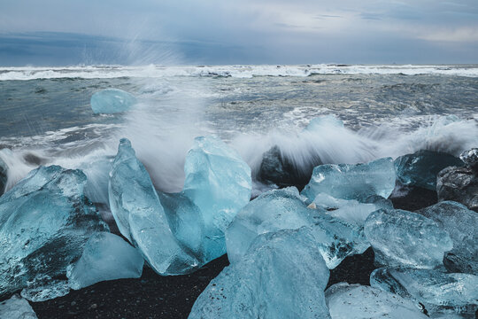 Chunks of glacier ice and crashing waves on black sand beach, Iceland