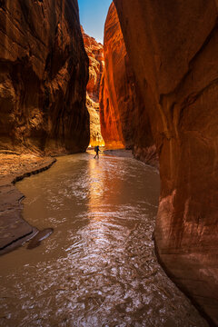 Backpacker walking through narrow Paria slot canyon