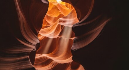 A sandstone canyon's interior; light beams cascade onto undulating walls of orange and brown