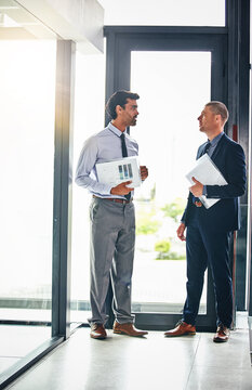 Folders, business men and discussion in office for meeting debrief, market insight or budget feedback. Financial analysts, team and talking with files at window for KPI review or investment follow up