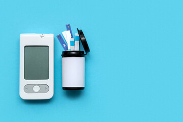 Naklejka premium White digital glucometer and box with test strips on blue background
