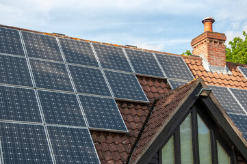 Closeup of solar panels installed on a modern house with a mock Tudor dormer window.