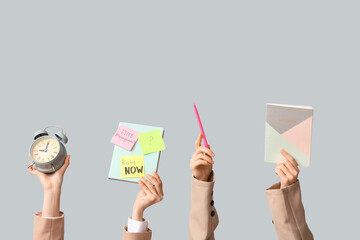 Female hands with alarm clock and notebooks on grey background. Time management concept