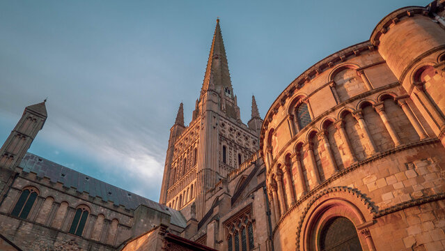 Norwich Cathedral in Norfolk, England in low winter sun with a cloudy background.