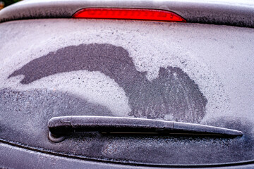 Frost forms on a car windshield during a cold morning in winter