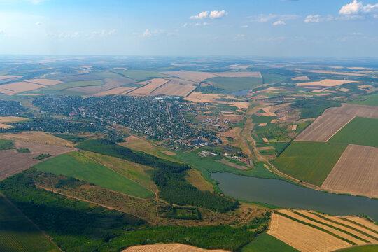 Detailed aerial view from airplane window of a small town with lake and surrounding green fields