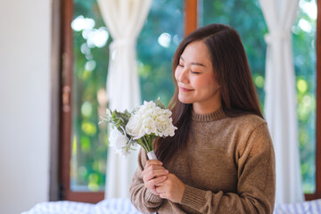 Portrait image of a beautiful woman holding a flower bouquet at home