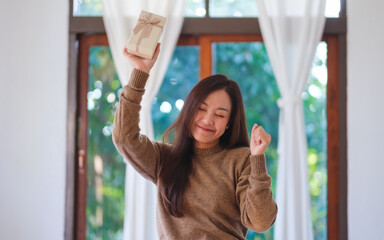Portrait image of a happy woman receiving a present box at home