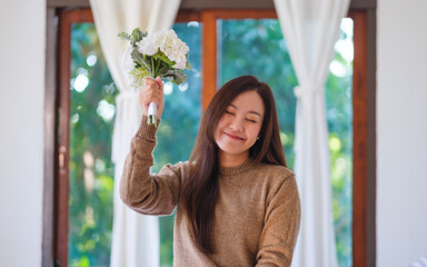 Portrait image of a happy woman holding a flower bouquet at home