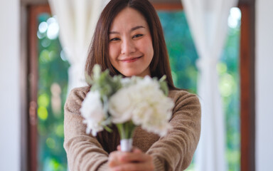 Portrait image of a beautiful woman holding and giving a white flower bouquet