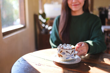 Closeup image of a woman holding a cup of hot chocolate with marshmallow