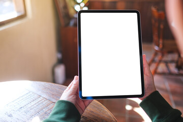 Mockup image of a woman holding digital tablet with blank white desktop screen in cafe