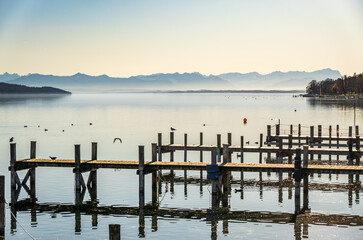 wooden pier with mountains in the distance, reflecting on calm water in the early morning light