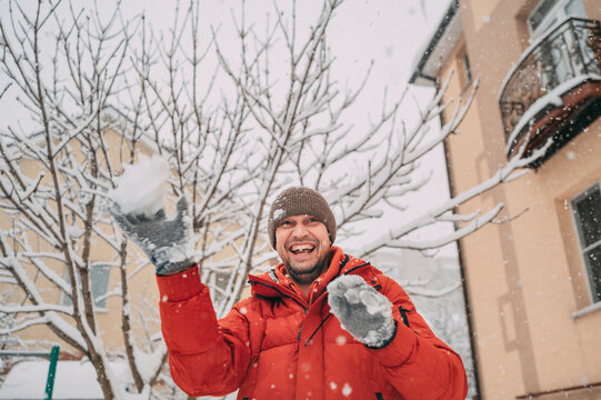 Smiling person in red jacket playing with snow outdoors in winter