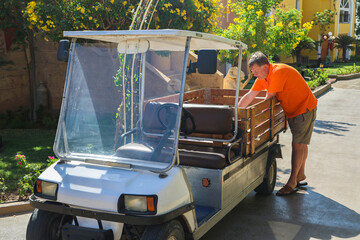 man loads things into the back of a small electric car near his home.