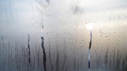 Glass condensation, window steam, water droplets, misted surface, cold weather effect, blurred glass, rainy day atmosphere, condensation droplets, texture, foggy window, wet glass background, moisture