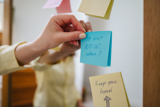 Hand placing positive affirmation sticky note with inspirational quote on mirror