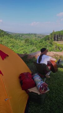 Asian women camping alone with mountain view. Solo outdoor activity and journey lifestyle on holiday.