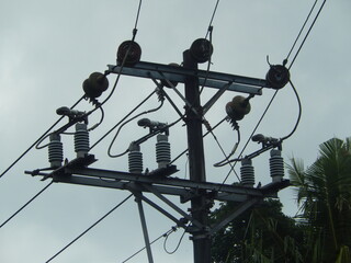 High Voltage Power Lines and Distribution Transformers on Concrete Utility Poles against Overcast Sky
