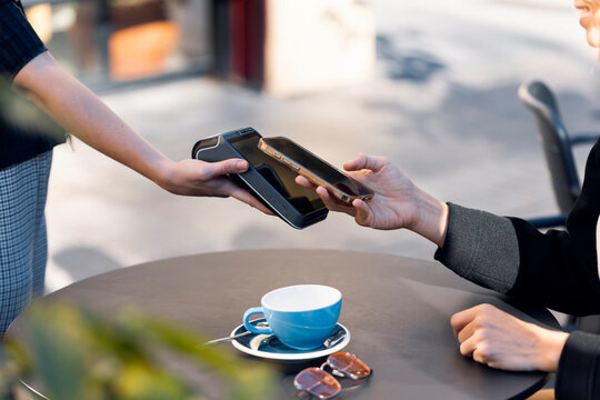 Contactless smartphone payment at outdoor caf� table with coffee cup