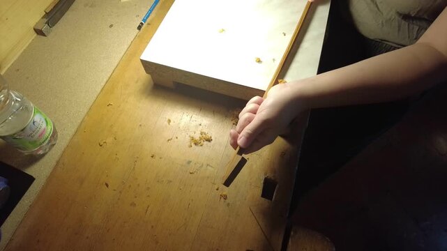 Craftsman's hands shaping a wooden bow stick for a violin instrument